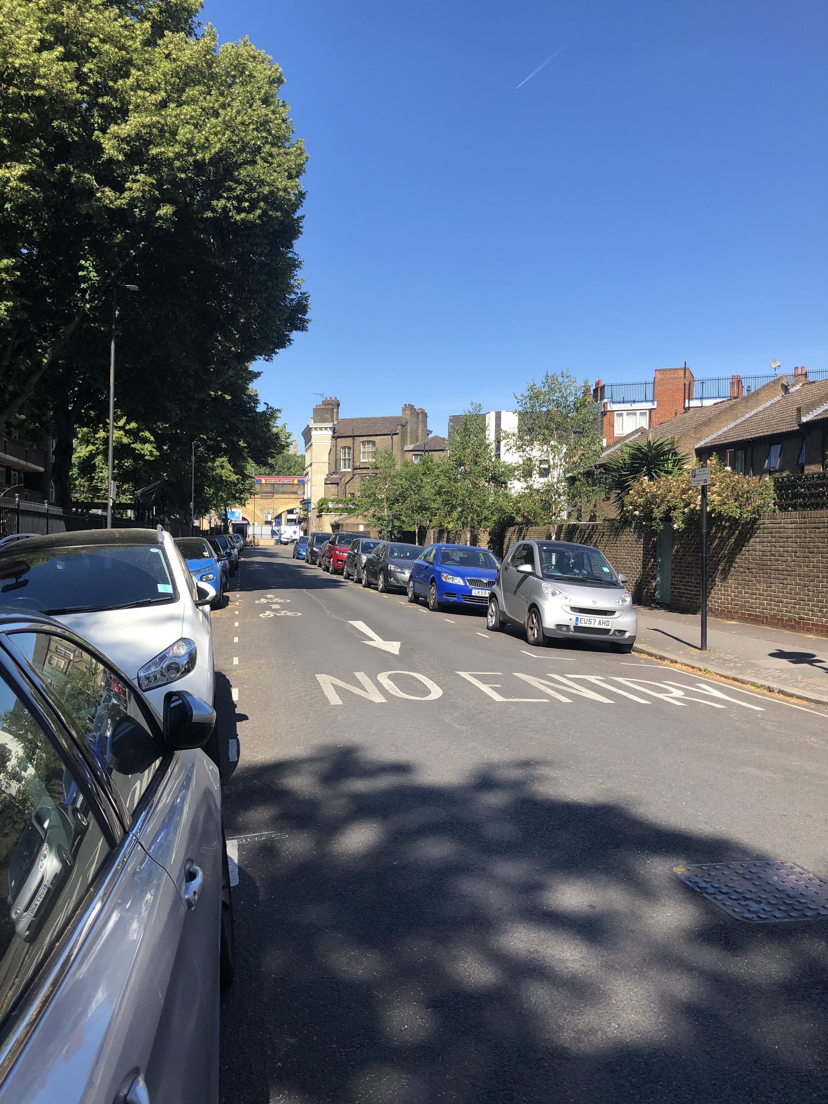 A residential street with parked cars and houses.