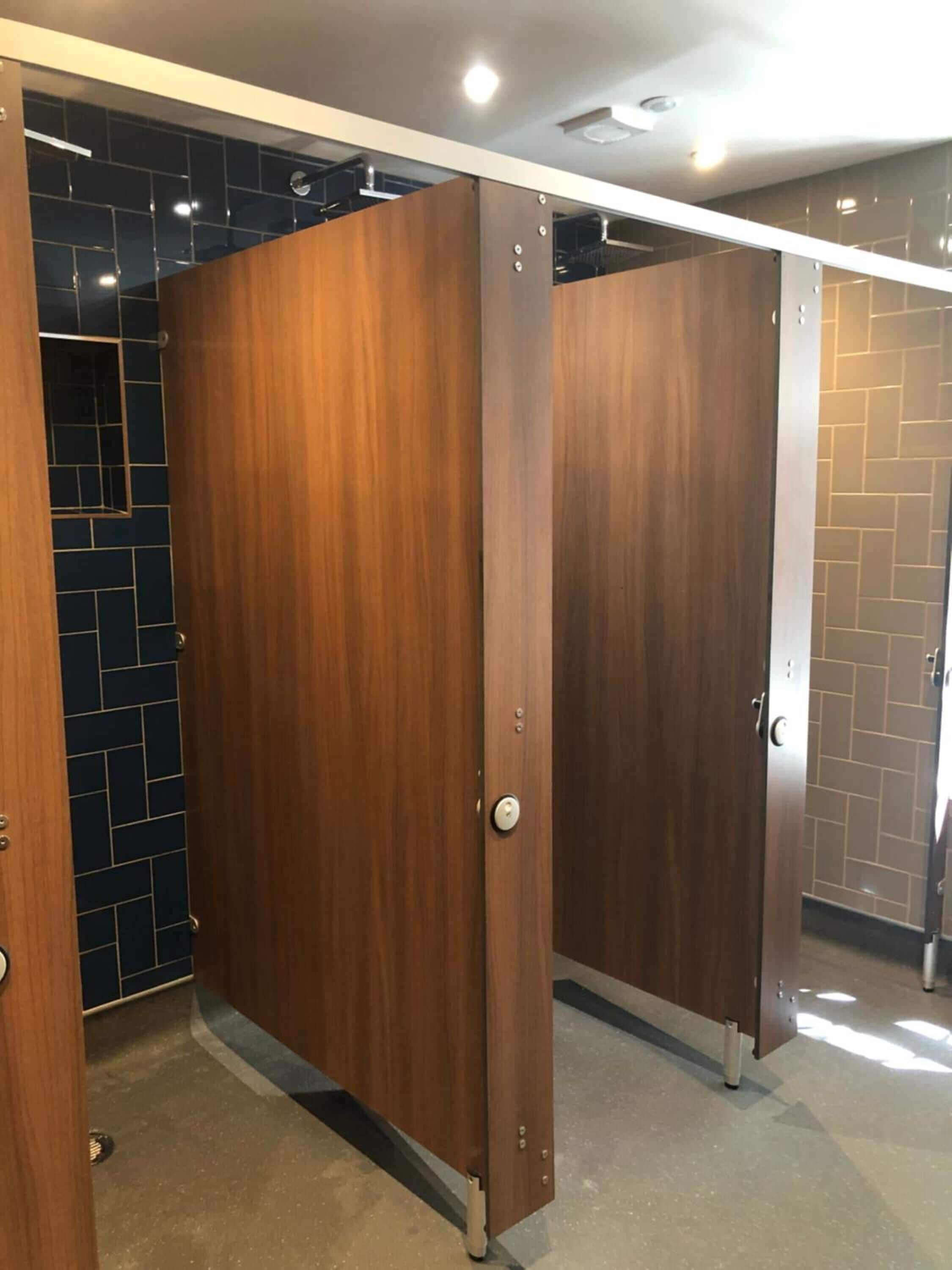 A public restroom with wooden partition stalls and tiled walls.
