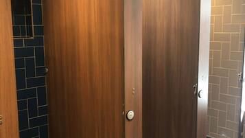 A public restroom with wooden partition stalls and tiled walls.
