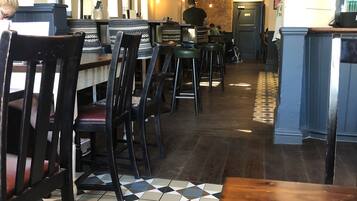A restaurant interior with a checkered floor, wooden tables, and black chairs.
