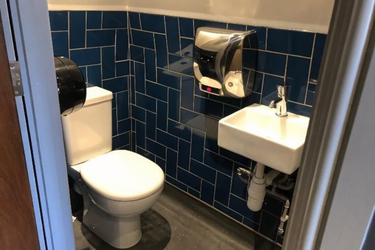 A small bathroom with a toilet, sink, and a paper towel dispenser.