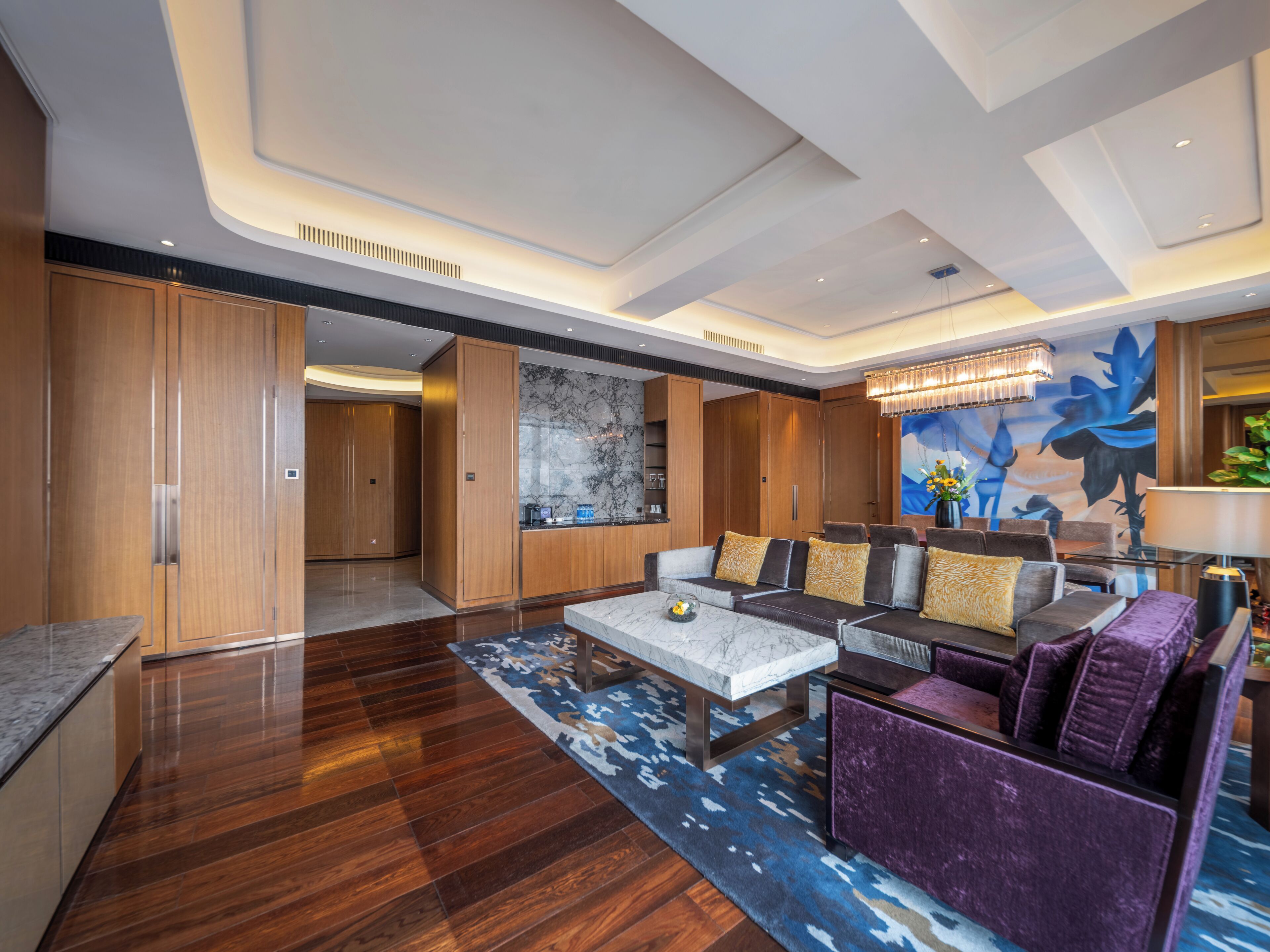 A spacious lobby with a marble coffee table, plush seating, and a large abstract mural.