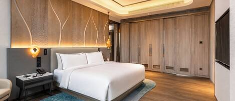 Una habitación de hotel moderna con una cama grande, un escritorio con teléfono, una silla y un armario.