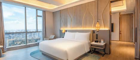 A modern hotel room with a large bed, a nightstand, a desk, a chair, a large window, and a city view.