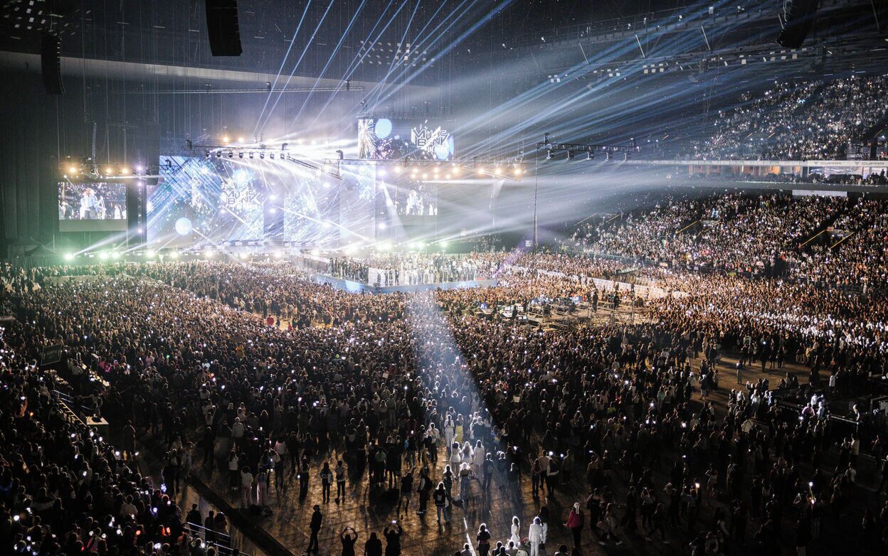 A large indoor venue with a central stage and multiple levels of seating.