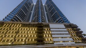 A modern hotel with a distinctive curved facade, multiple balconies, and a well-lit entrance.