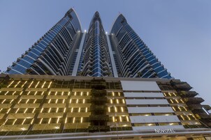 Un hotel moderno con una fachada curva distintiva, varios balcones y una entrada bien iluminada.