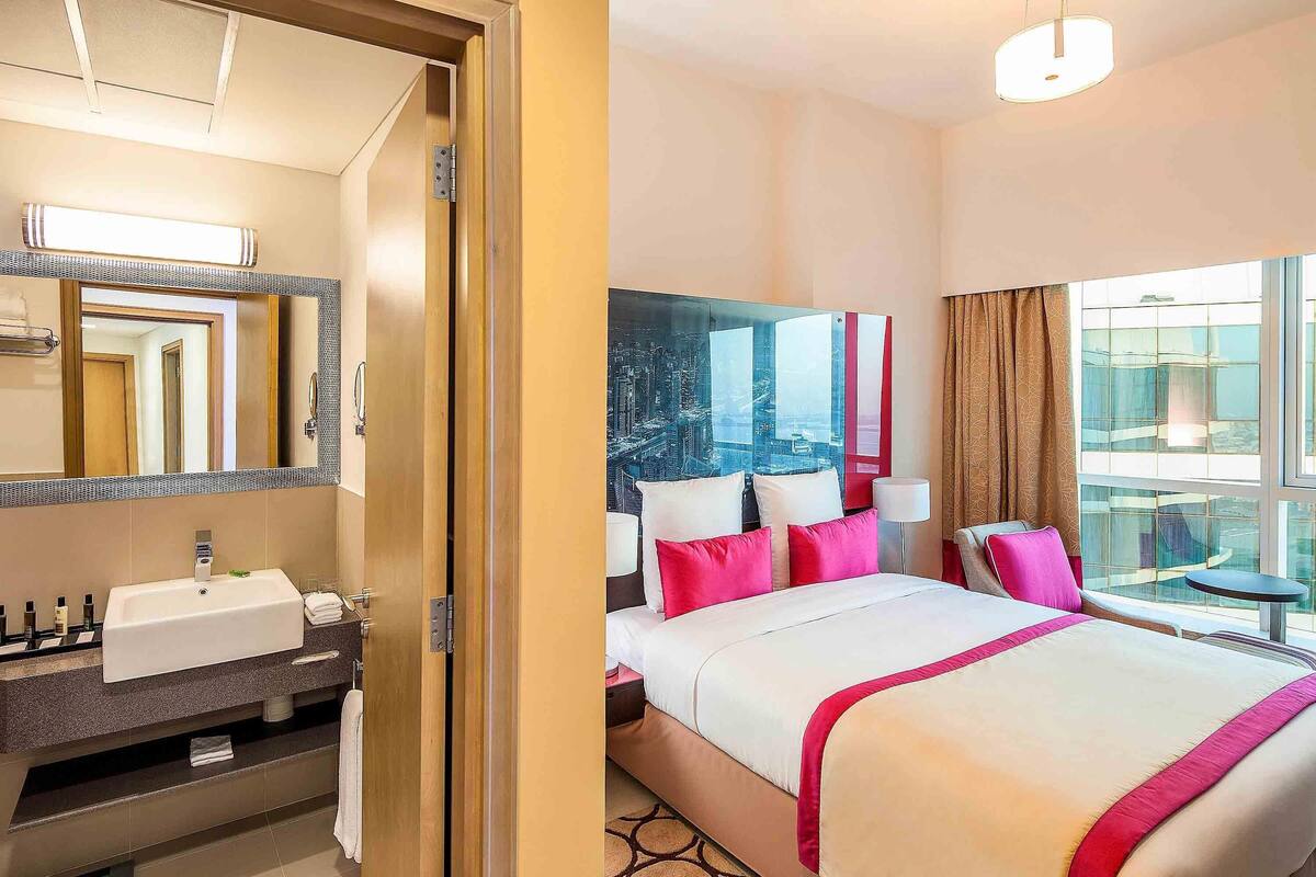 Ein Hotelzimmer mit Bett, Badezimmer und großem Fenster.