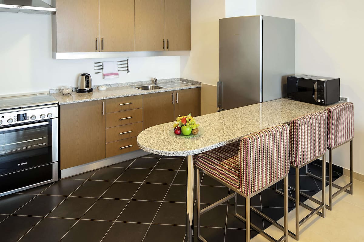 A modern kitchen with wooden cabinets, a stainless steel stove, a refrigerator, and a microwave.
