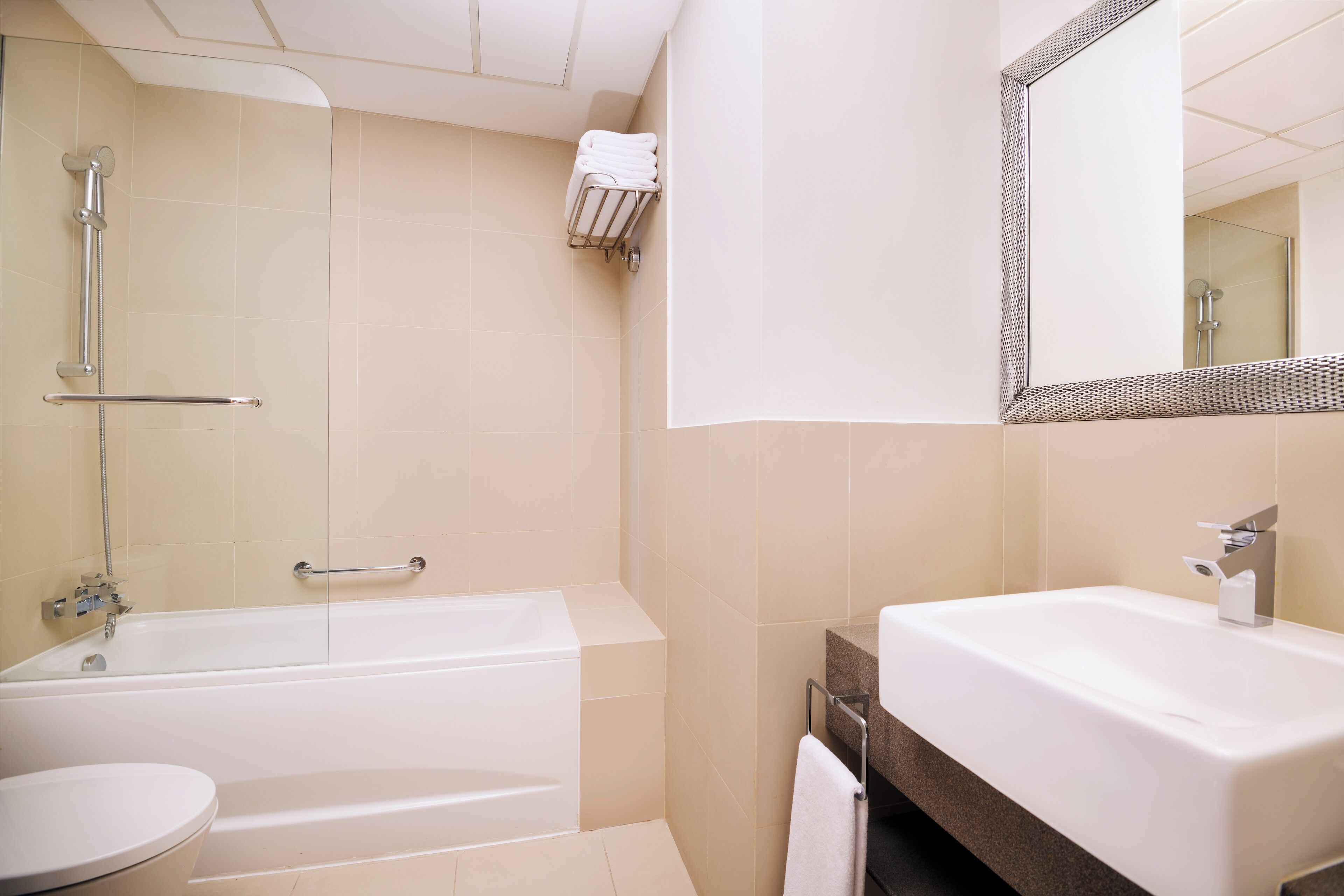 A modern bathroom with a bathtub, toilet, and sink, featuring a glass shower enclosure and a large mirror.