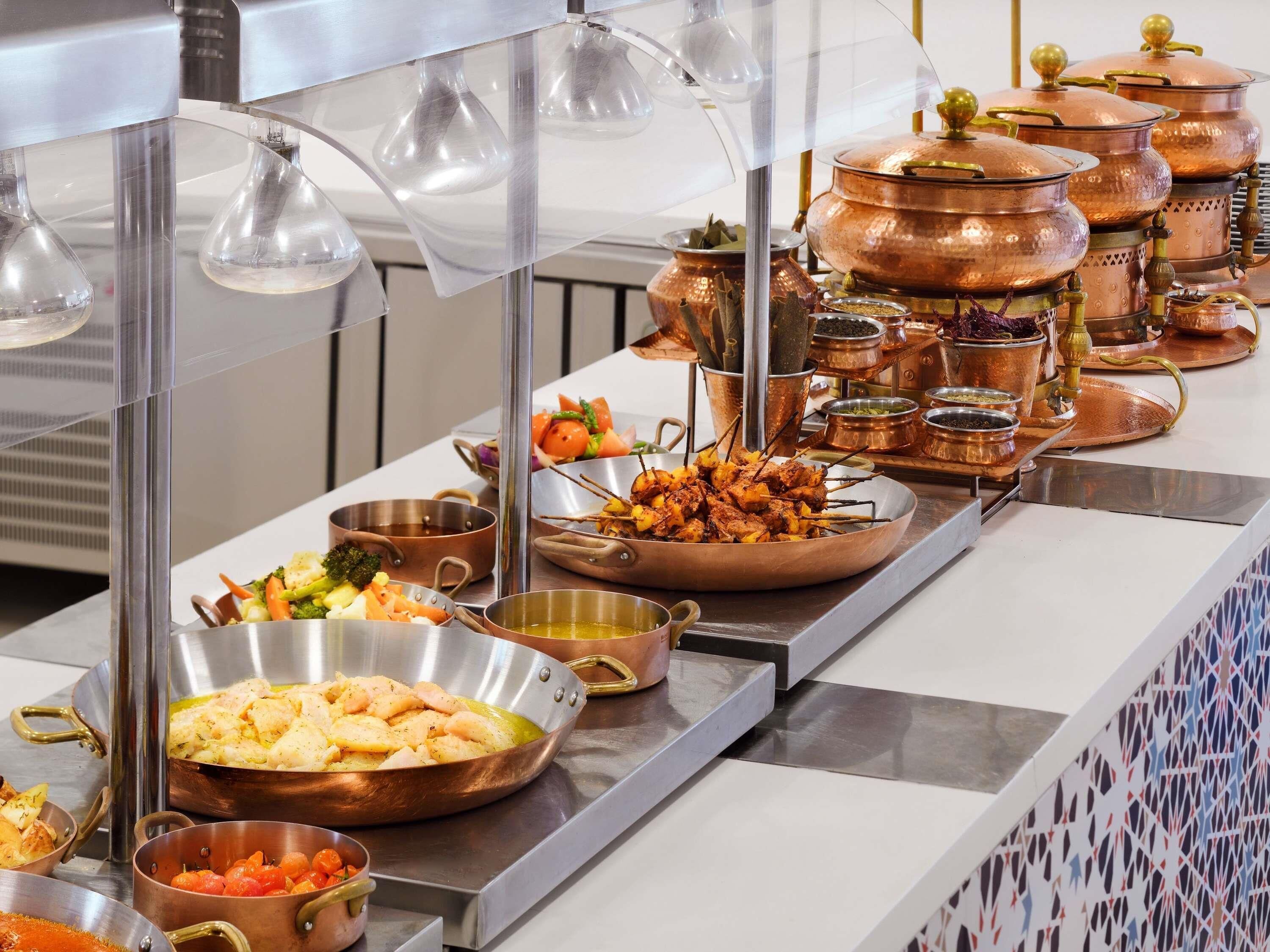 Una barra de buffet con diversos alimentos y utensilios de cocina.