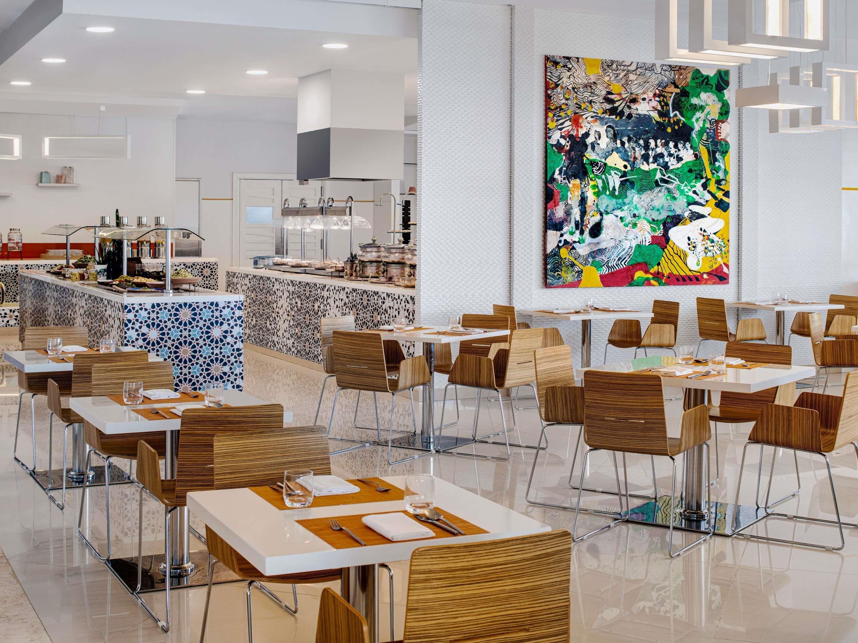A modern dining area with a central island, bar seating, and a large abstract painting on the wall.
