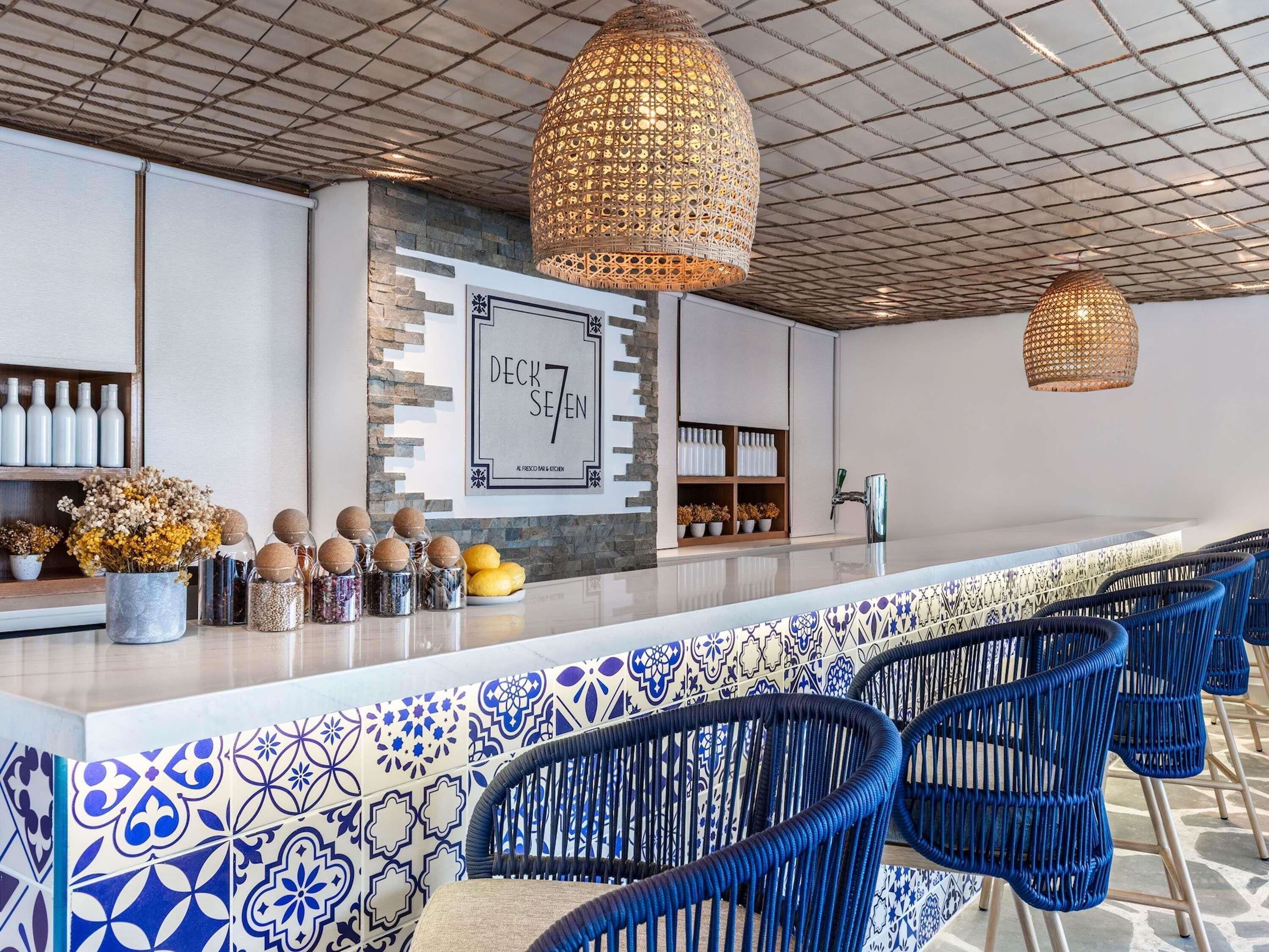 A modern kitchen with a central island, blue wicker chairs, and decorative items.