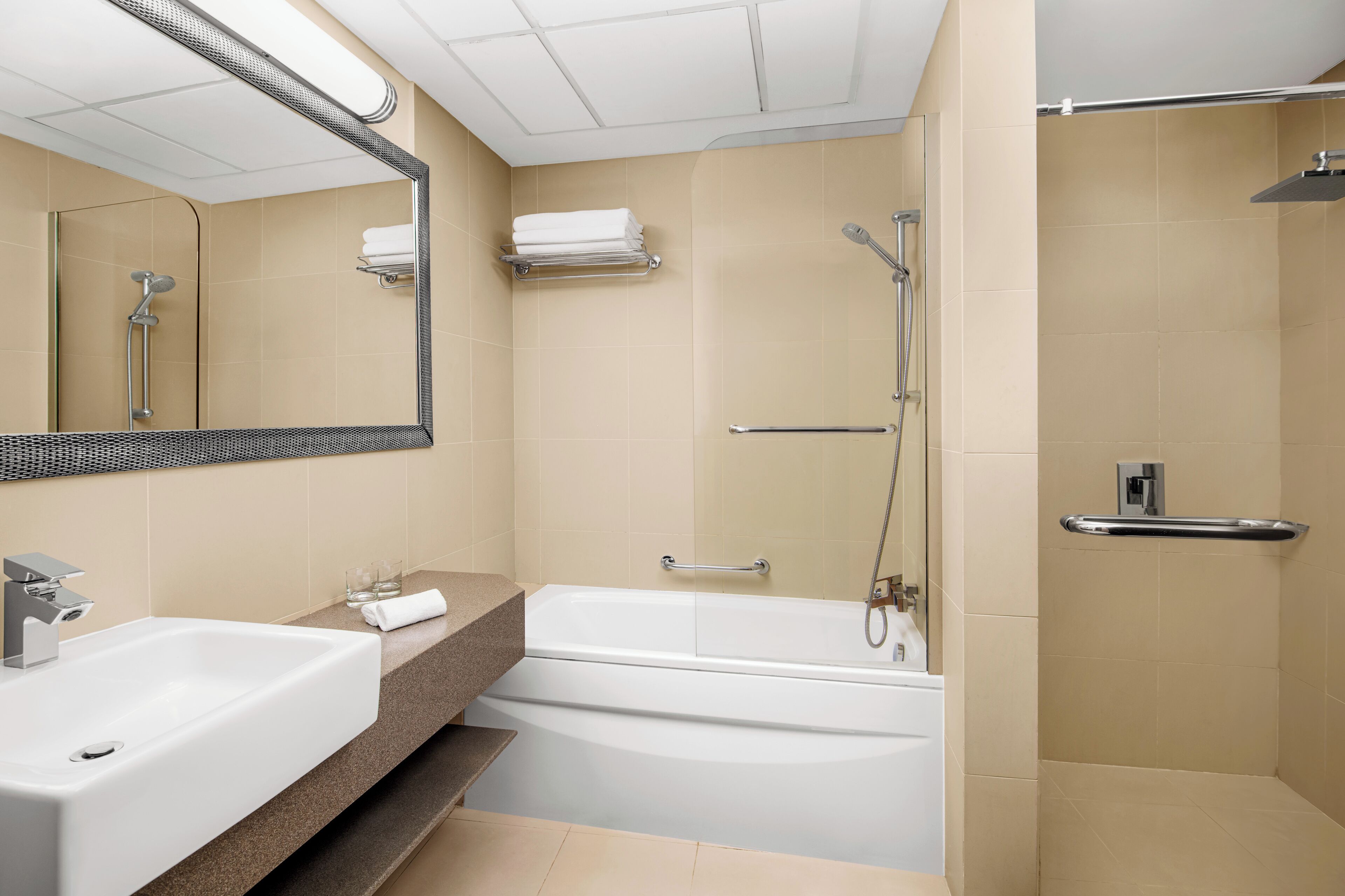 A bathroom with a sink, mirror, bathtub, shower, and towel rack.