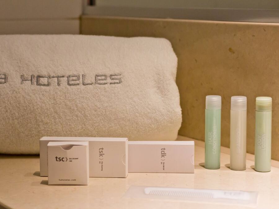 A bathroom with a towel, a comb, and three bottles of hair care products.