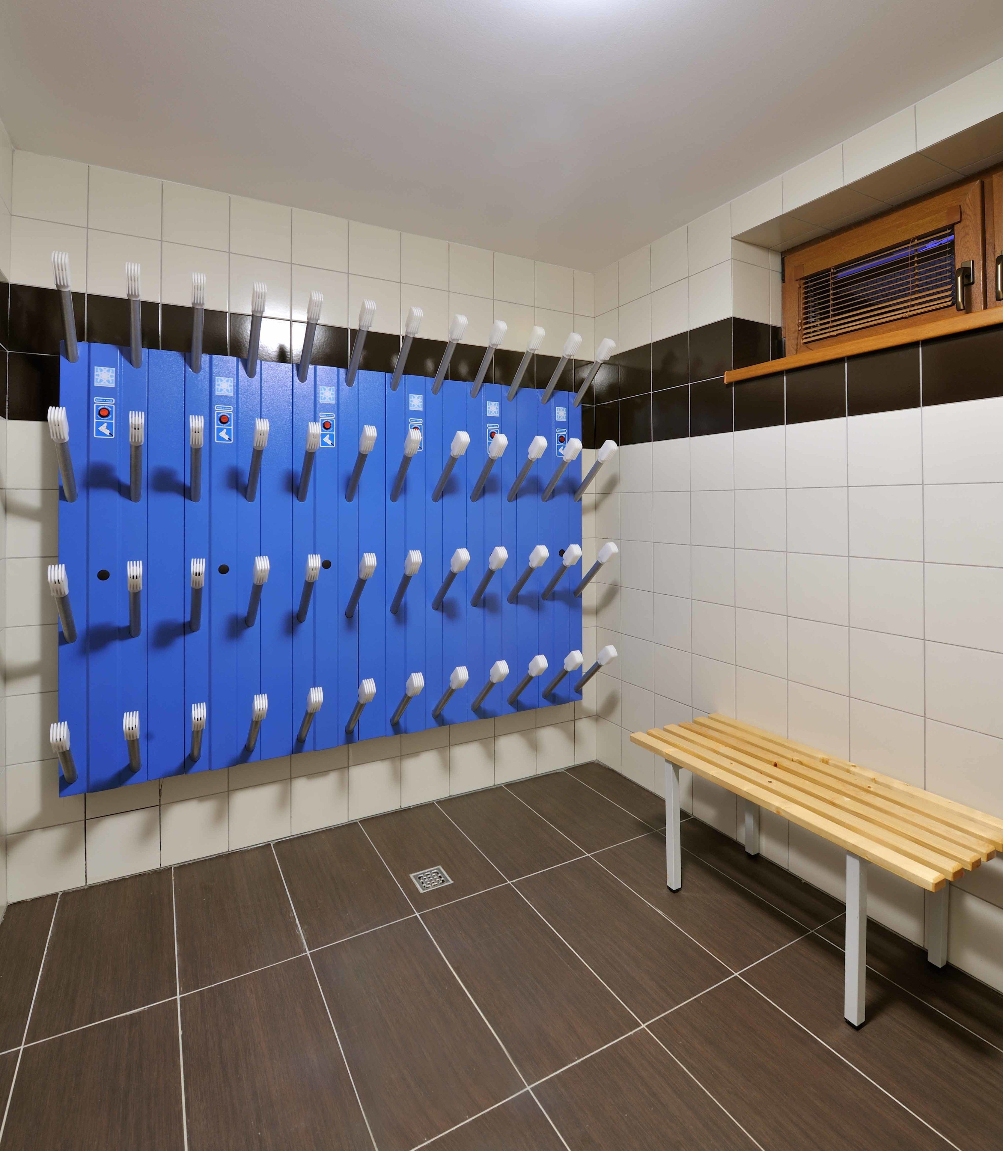 Des toilettes équipées de plusieurs supports à brosses à dents, d’un banc et de murs carrelés.