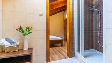 Een badkamer met een douche, een houten plafond en een witte betegelde muur.