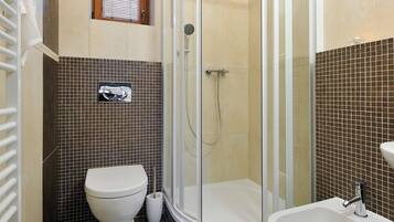 A bathroom with a glass-enclosed shower, a toilet, a bidet, and a sink.
