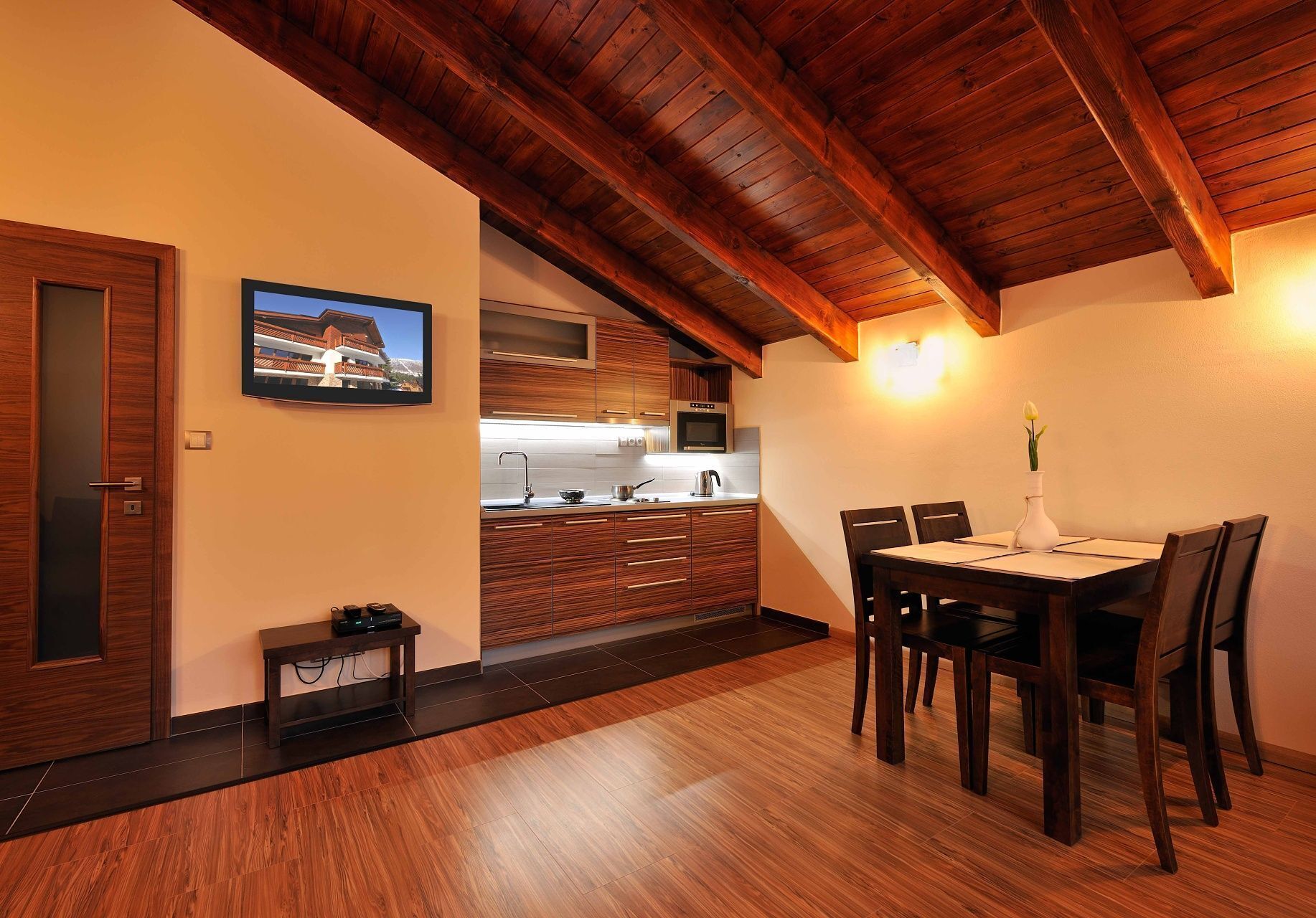 A modern kitchen with wooden cabinets, a dining table with chairs, and a wooden ceiling.