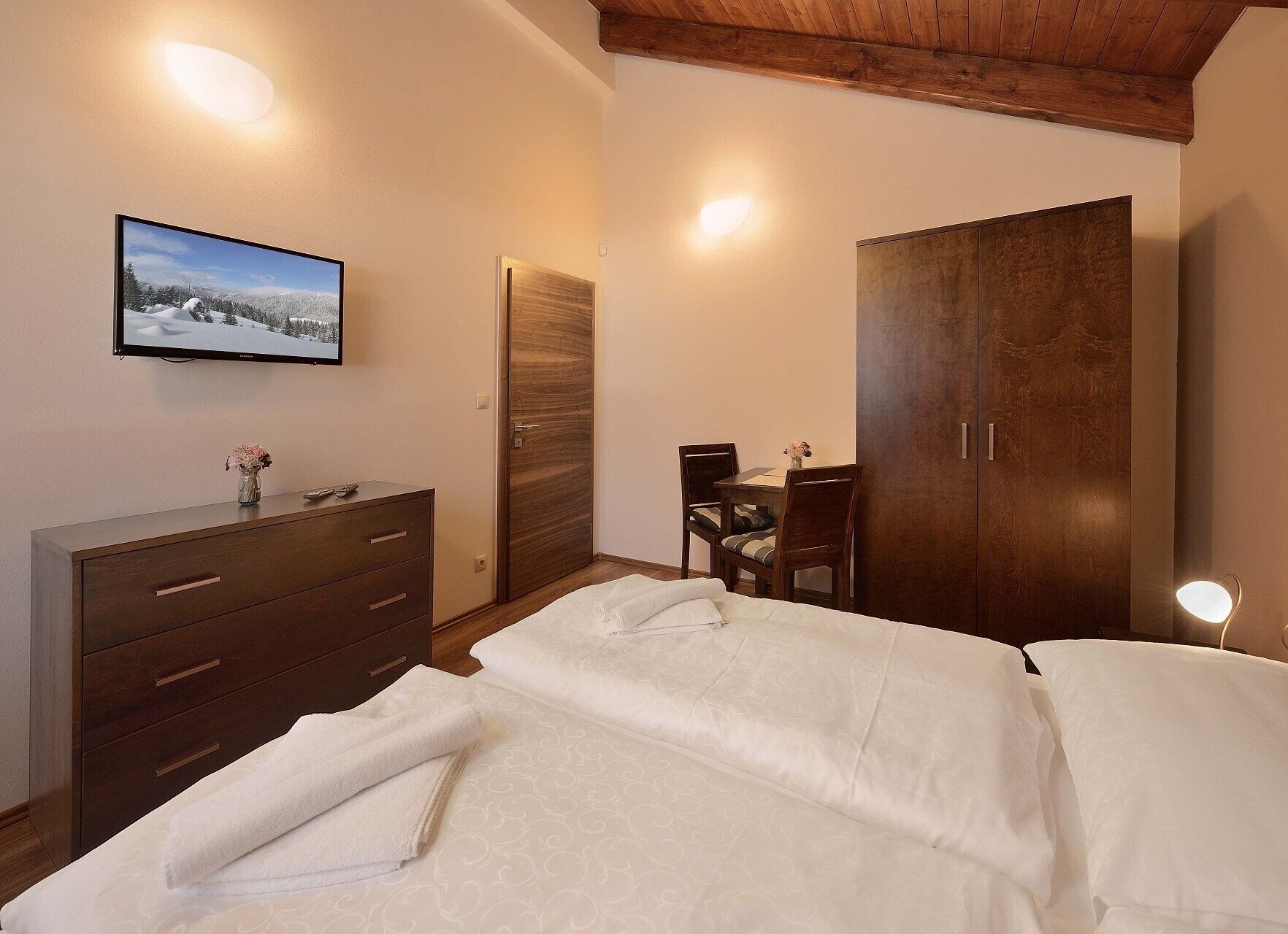 A bedroom with a bed, a dresser, a desk with a chair, and a wardrobe.