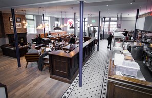 A modern restaurant with a bar area, seating, and a kitchen visible.