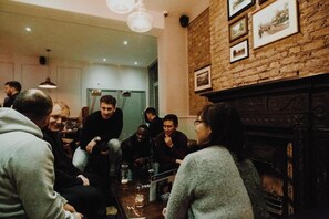 A group of people seated around a table in a room with a brick wall and a fireplace. - PubLove @ The Crown, Battersea - Hostel (London)