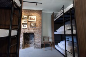 A room with bunk beds, a brick fireplace, and framed pictures on the wall.