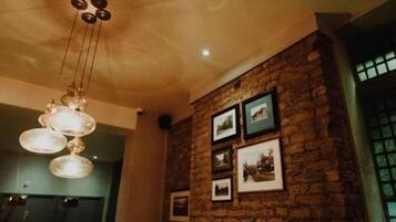 A room with a stone wall, a chandelier, and framed pictures.