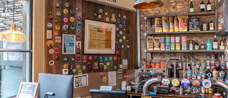 Eine Bar mit einer Holzwand, die mit Bierkorken verziert ist, einer Kasse und Regalen voller verschiedener Flaschen.