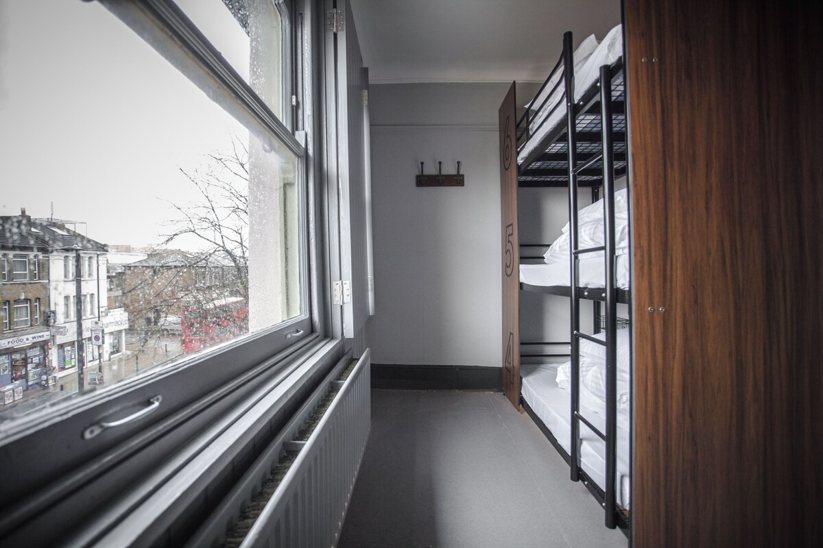 A narrow corridor with bunk beds on one side and a window on the other.