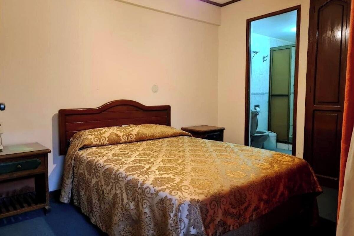 Un dormitorio con una cama de madera, una mesita de noche y un tocador.