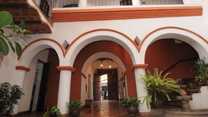 Un patio con arcos, plantas en macetas y una escalera.