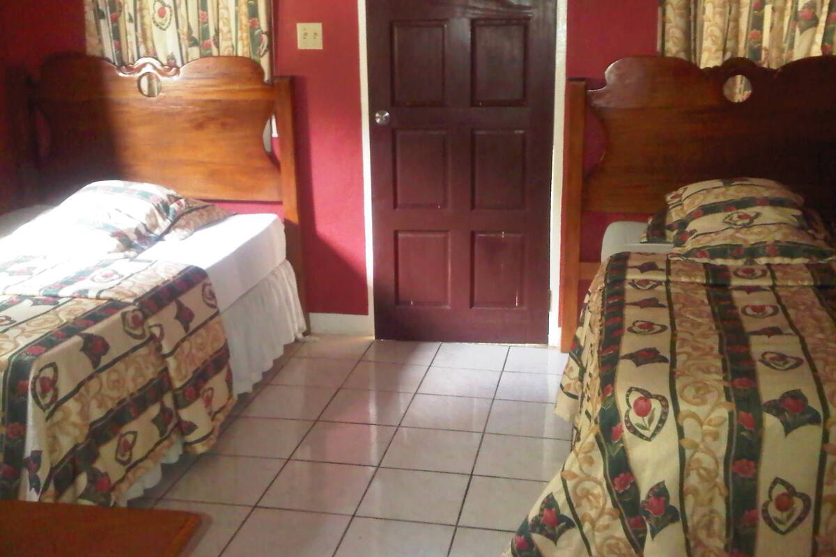 A bedroom with two beds, a wooden door, and a tiled floor.