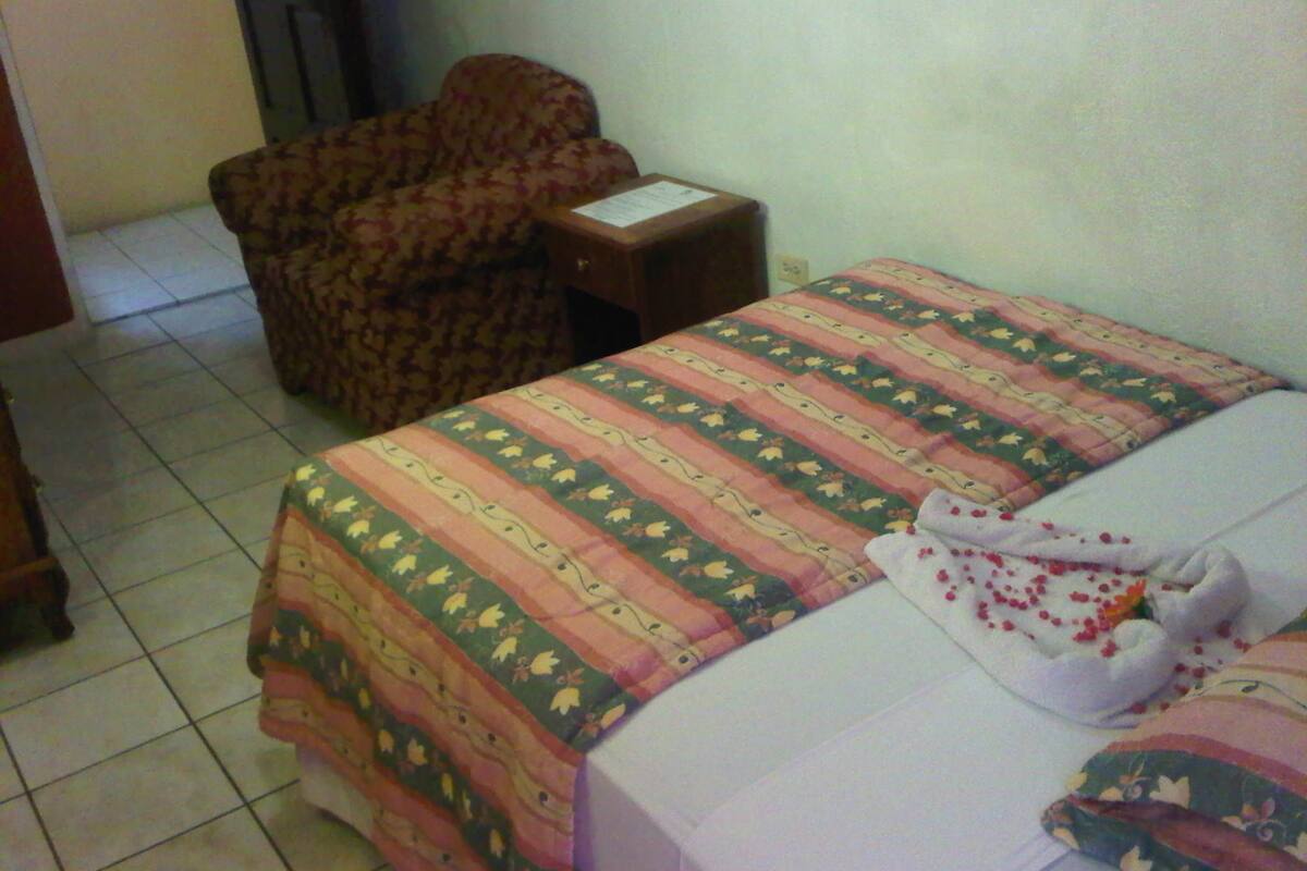 A bedroom with a bed, a chair, and a small table.