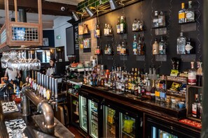 A bar area with a variety of liquor bottles, a beer tap, and a refrigerated display. - PubLove @ The Green Man - Hostel (London)