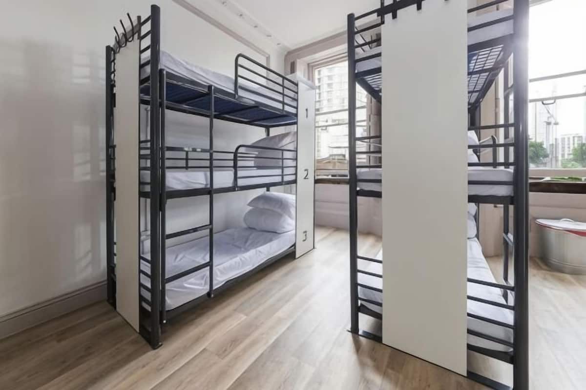 Une chambre avec des lits superposés offrant une vue sur la ville par une fenêtre.
