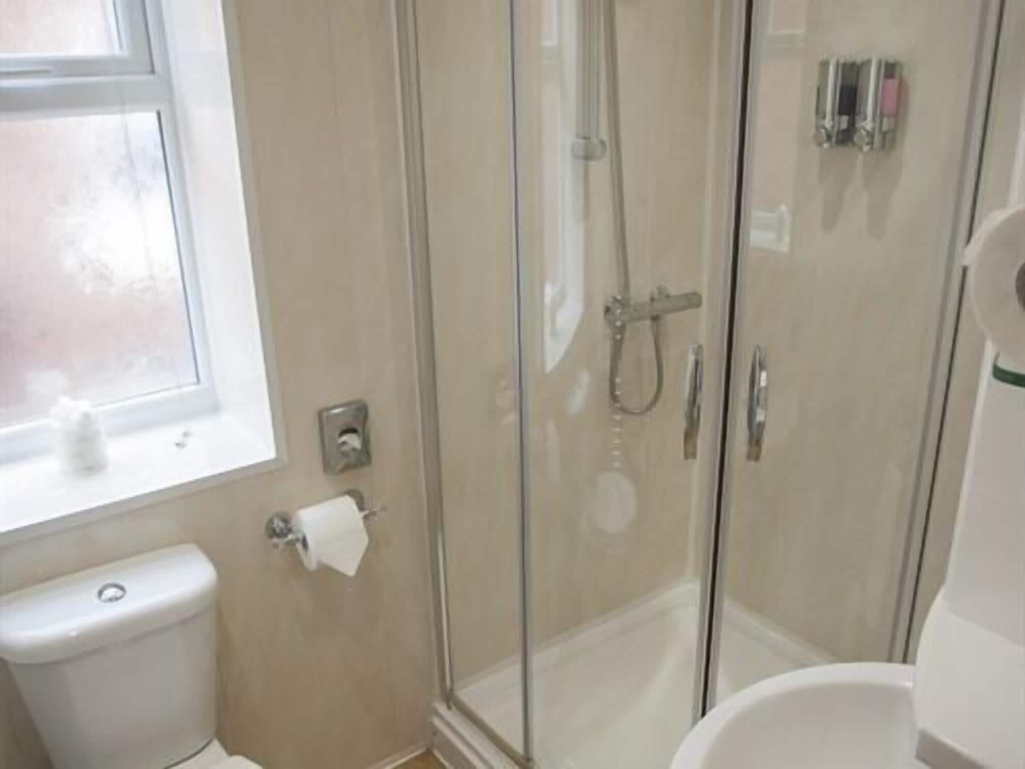 A bathroom with a toilet, a glass-enclosed shower, and a bathtub.