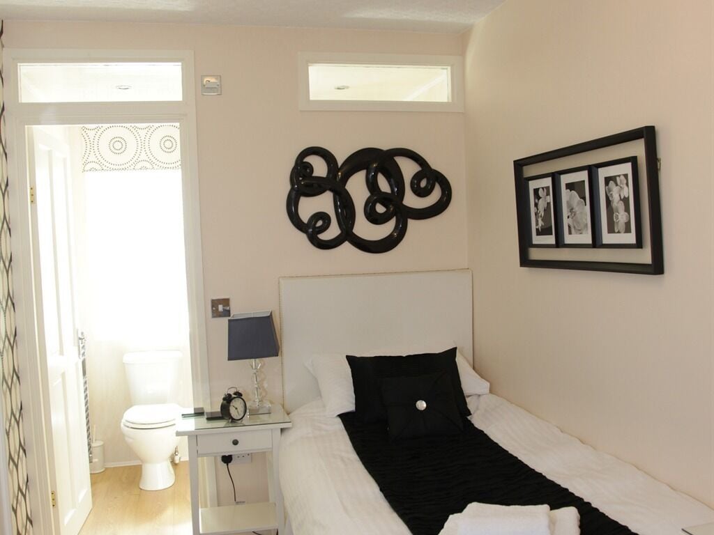Un dormitorio con una cama, una mesita de noche con lámpara, una obra de arte en la pared y un cuadro enmarco.