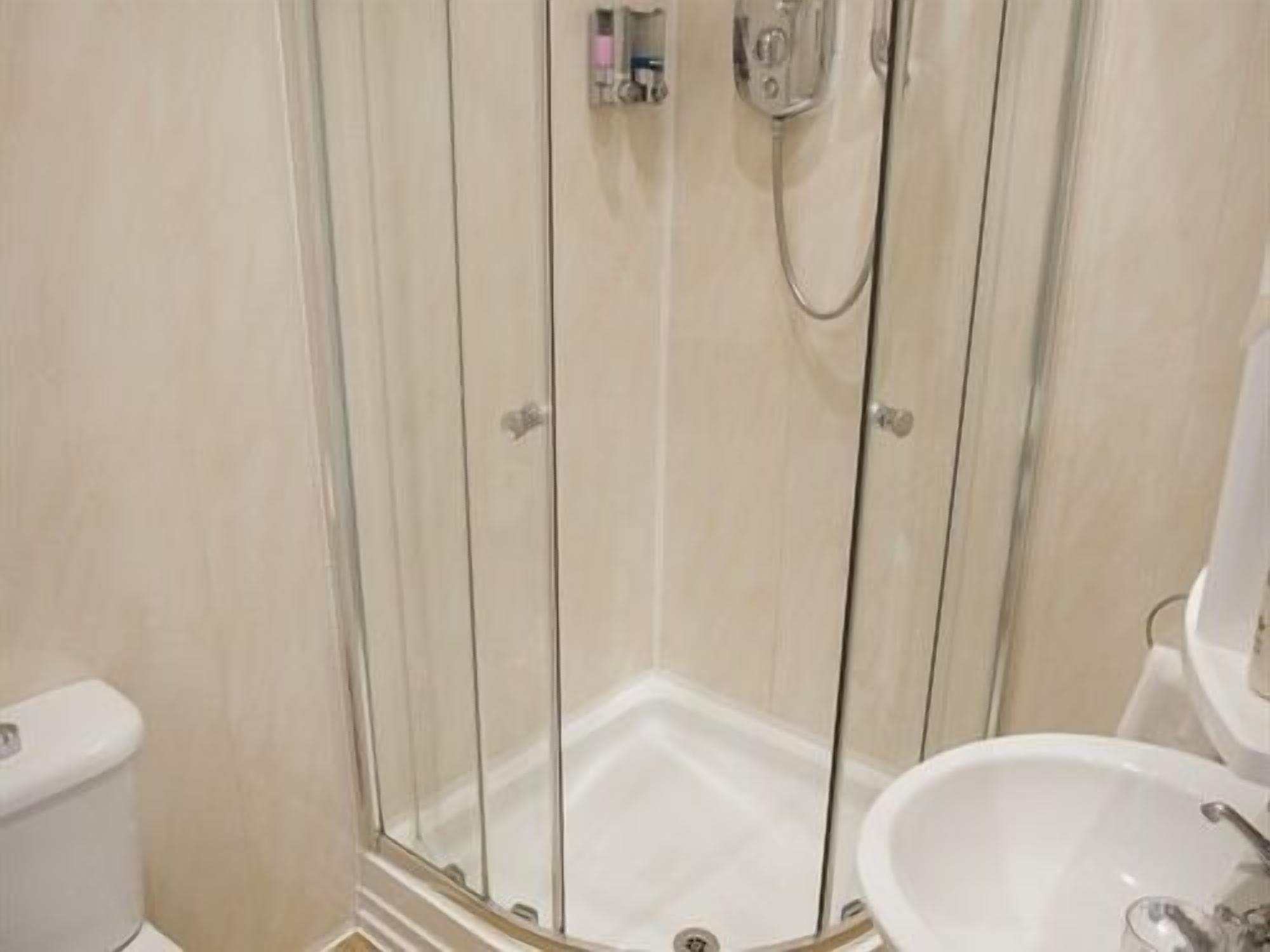 A bathroom with a glass-enclosed shower, a white sink, and a toilet.