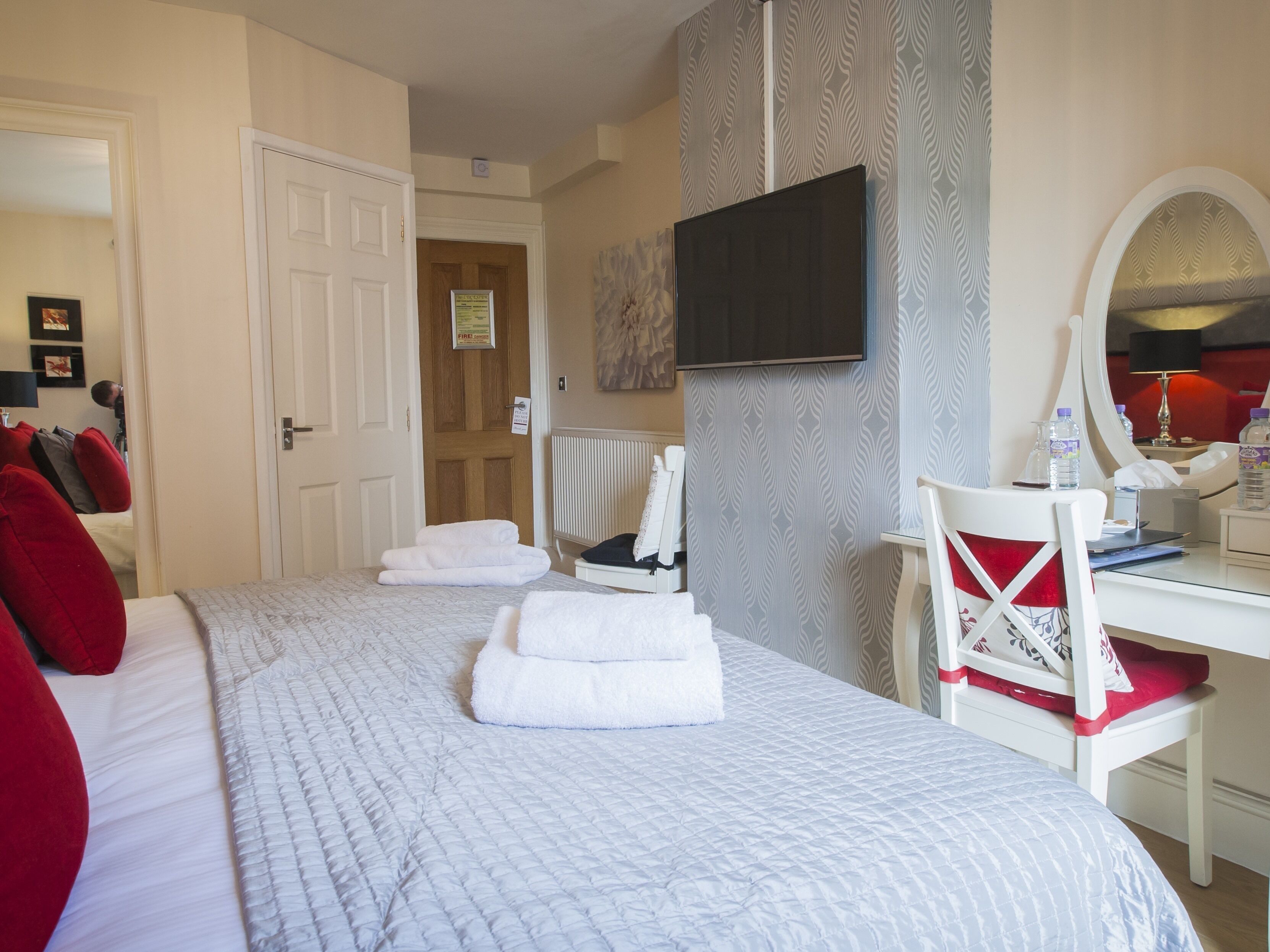 Een hotelkamer met een bed, een bureau, een stoel, een spiegel en een televisie.