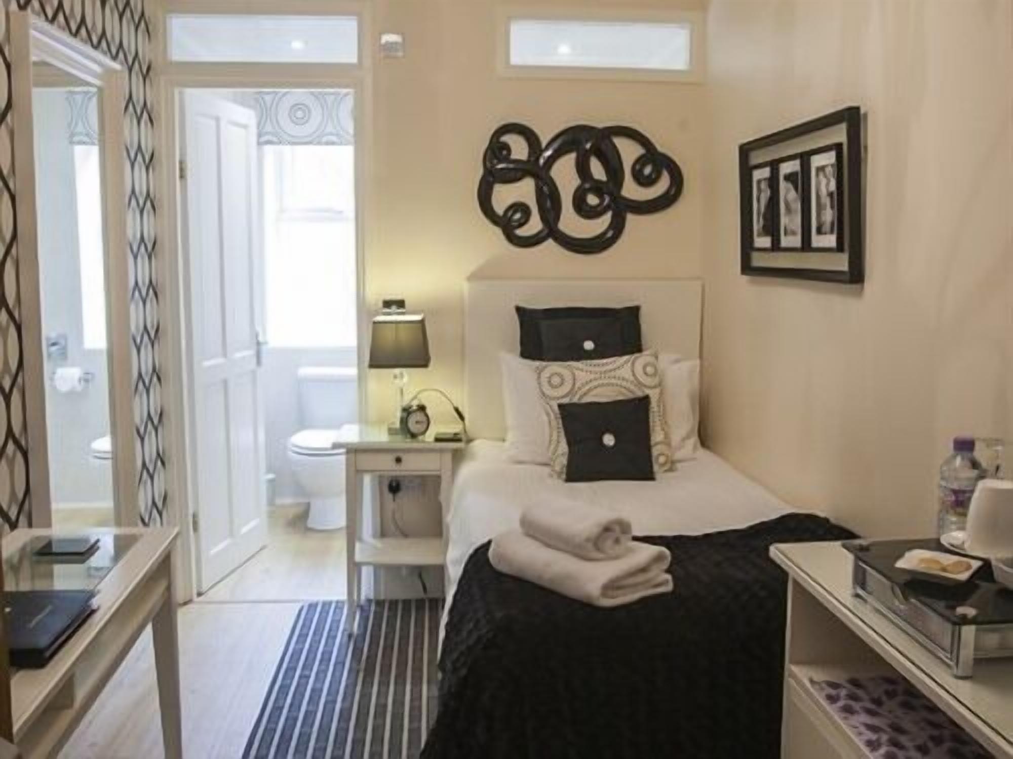 A hotel room with a bed, bedside table, lamp, and a wall-mounted artwork.