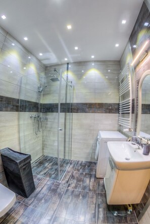 Ein modernes Badezimmer mit einer gläsernen Duschkabine, einem Waschbecken und einer Toilette.