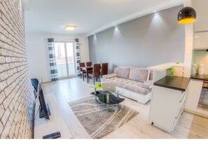 Un salon moderne avec un canapé, une table basse en verre et un coin repas avec des chaises.