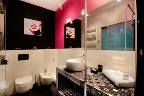 Une salle de bain moderne avec un mur recouvert de carreaux noirs et blancs, un lavabo blanc et un bidet.