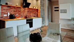 Een moderne keuken met een tegelwand, een centraal eiland en een eethoek met witte stoelen en een glazen tafel.