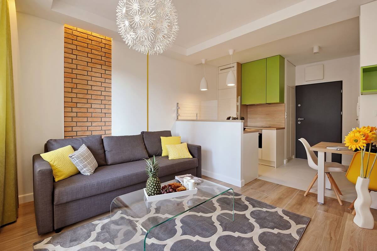 Una sala de estar moderna con un sofá gris, una mesa de centro de vidrio y un tapete estampado.