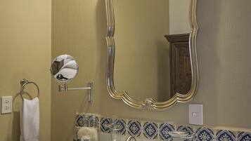 A bathroom with a marble sink, a large ornate mirror, and a towel ring on the wall.