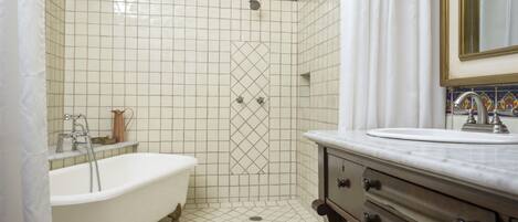 A bathroom with a bathtub, a shower, and a sink with a mirror.