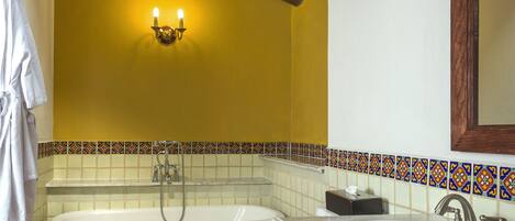 A bathroom with a bathtub, toilet, and sink, featuring wooden beams, tiled walls, and a mirror.