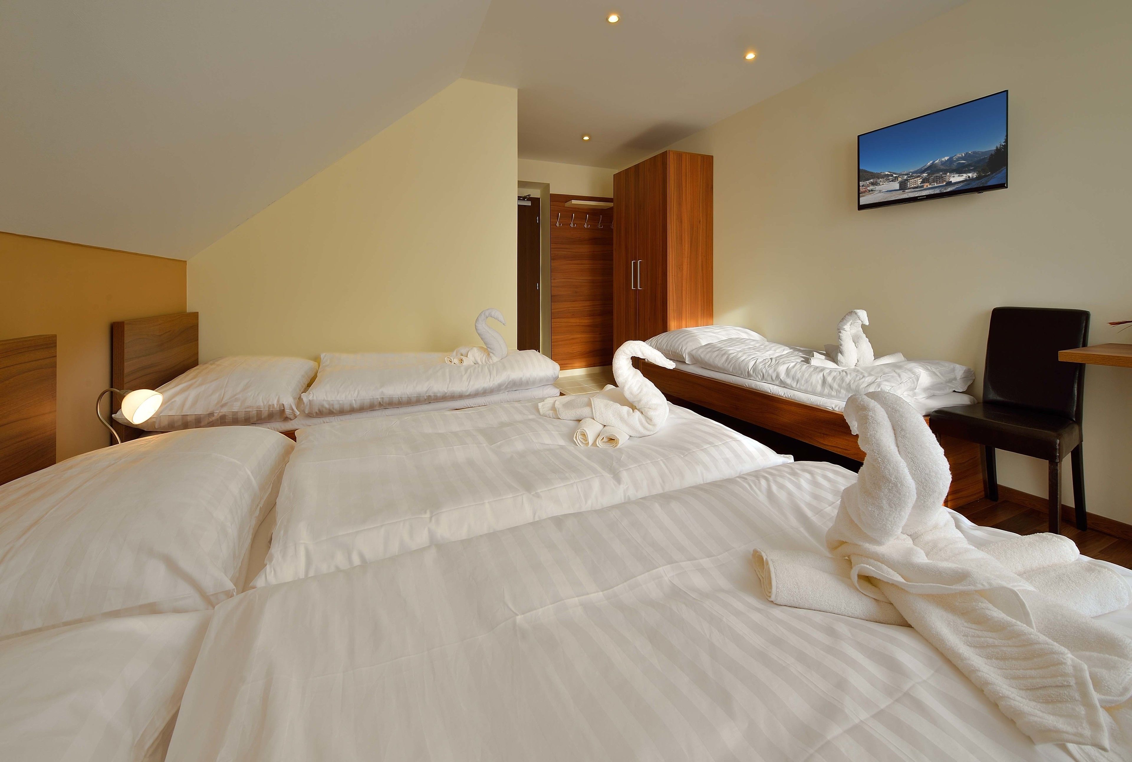 A hotel room with two beds, a wooden wardrobe, a television, and a painting on the wall.